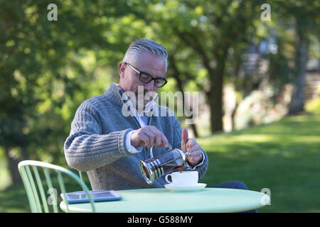 Genießen einen Kaffee in seinem Garten an einem sonnigen Morgen Mann Stockfoto