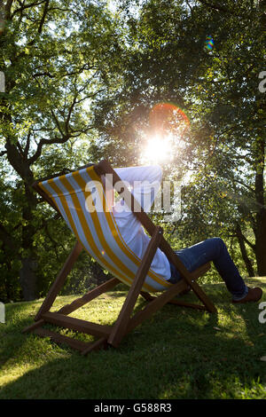 Entspannen Sie sich auf einen Liegestuhl in seinem Garten reifer Mann Stockfoto