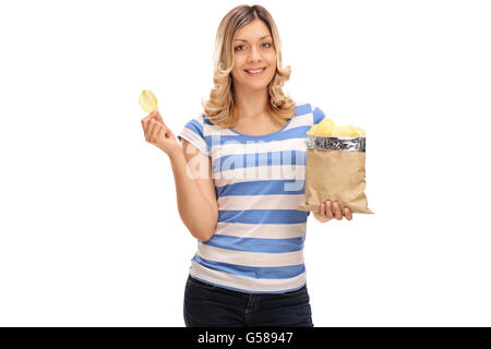 Fröhliche blonde Frau Essen Kartoffelchips und schaut in die Kamera, die isoliert auf weißem Hintergrund Stockfoto