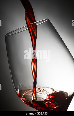 Nahaufnahme der Füllung ein Glas Rotwein vor dem Studio-Hintergrund leuchtet auf Stockfoto