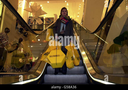 Die Shopper Laura Cooty trägt ihre Einkaufstüten im Londoner Kaufhaus Selfridges über eine Rolltreppe, während der Verkauf im Januar beginnt. Stockfoto