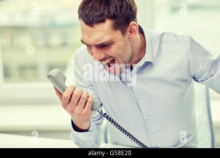 wütend Geschäftsmann fordert Telefon im Büro Stockfoto