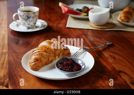 Croissants mit Marmelade und Kaffee auf Holztisch. Stockfoto