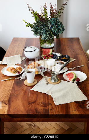 Frühstück. Heiße Getränke, Croissants, Obst auf dem Holztisch. Stockfoto