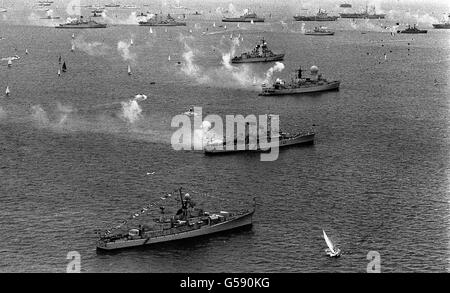 Kriegsschiffe feuern einen 21-Kanonen-Gruß entlang der 7 Meilen-Überprüfungslinie bei der Silver Jubilee Review of the Fleet, die von der Queen an Bord der Royal Yacht Britannia in Spithead genommen wurde. Stockfoto