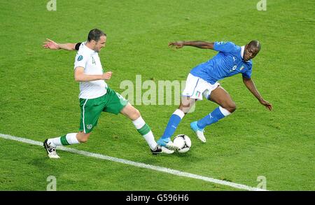 Fußball - UEFA Euro 2012 - Gruppe C - Italien / Republik Irland - Stadtstadion. Der Repräsentant von John O'Shea (links) und Mario Balotelli, der Italiener, kämpfen um den Ball Stockfoto