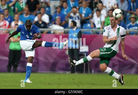 Fußball - UEFA Euro 2012 - Gruppe C - Italien / Republik Irland - Stadtstadion. Der Italiener Mario Balotelli (links) hat unter dem Druck von Richard Dunne, Irlands Republik, einen Torschuss erhalten Stockfoto