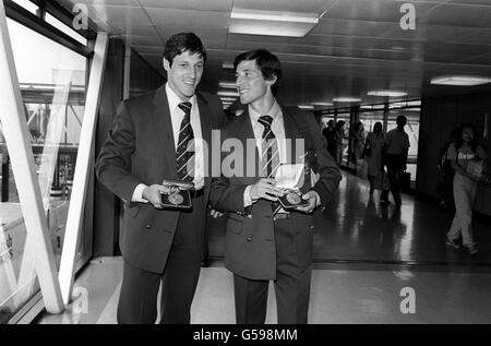 Die Athleten Allan Wells, Left, und Sebastian Coe zeigen stolz ihre olympischen Goldmedaillen am Flughafen Heathrow, als sie von den Moskauer Spielen zurückkehrten. Die Bohrlöcher gewannen Gold in den 100 Metern und Silber in den 200 Metern, während Coe Gold in den 1500 Metern und Silber in den 800 Metern gewann. Stockfoto