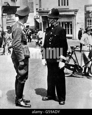 Ein Offizier der Luftwaffe, der während der deutschen Besetzung der Kanalinseln mit einem britischen Polizisten in St. Helier, der Hauptstadt der Insel Jersey, sprach. Stockfoto