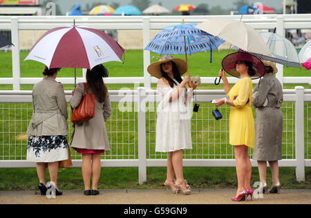 Pferderennen - The Royal Ascot Meeting 2012 - Tag Drei - Ascot Racecourse. Rennfahrer mit Regenschirmen am dritten Tag des Royal Ascot-Treffens 2012 auf der Ascot Racecourse, Berkshire. Stockfoto