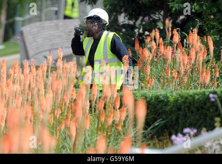 Olympische Spiele - Olympische Park Final Preparations. Ein Arbeiter singt, während er Blumen im Olympiapark in Stratford, London, pflanzt. Stockfoto