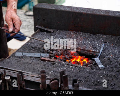 Schmied ist ein Stück Eisen in der heißen Schmiede Erweichung. Stockfoto