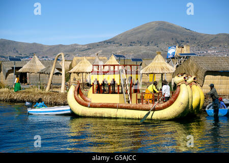 Gelbe Totora-Schilf-Boot und Häuser auf Totora Schilf Insel, Inseln der Uros, Titicaca-See, Puno, Peru Stockfoto