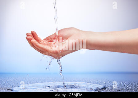 Wasser im Womans Hand auf weißen und blauen Hintergrund Stockfoto