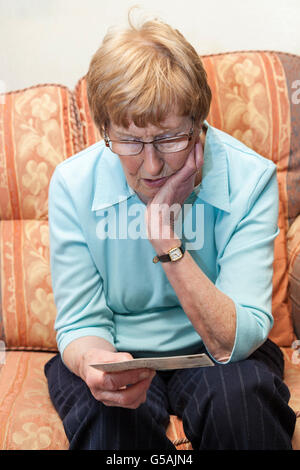 Ältere Frau betrachten Postkarte Stockfoto