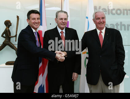 Präsident Jacques Rogge (Mitte) wird von Lord Sebastian Coe (links) und dem IOC-Mitglied für Großbritannien Sir Craig Reedie bei seiner Ankunft zu den Olympischen Spielen 2012 in London am Flughafen Heathrow begrüßt. Stockfoto