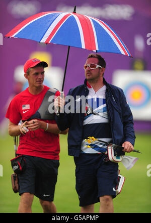 Der britische Larry Godfrey (rechts) kehrt in seine Schießposition zurück, wobei der US-Amerikaner Jacob Wukie (links) während der Einzelrangliste der Männer im Bogenschießen auf dem Lords Cricket Ground, London, einen Regenschirm hält. Stockfoto