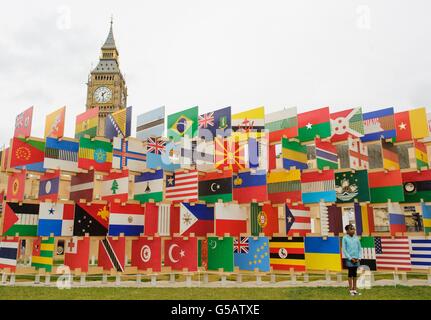 Ein Mädchen posiert neben einem Kunstwerk von Nationalflaggen der konkurrierenden olympischen Nationen, auf dem Parliament Square im Zentrum von London. Stockfoto