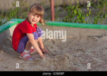 Kleines Mädchen im Sandkasten spielen, an einem sonnigen Sommertag Stockfoto