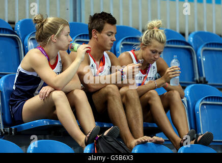 Der britische Tom Daley (Mitte) benutzt sein Telefon, während er mit der Tonia Couch (rechts) während einer Trainingseinheit im Aquatic Centre, Olympic Park, London sitzt. Stockfoto