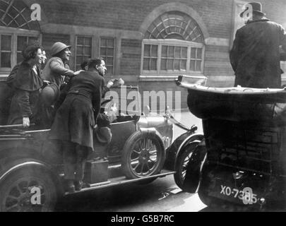 Winston Churchill, ganz rechts, steht in einem Auto, während er von verhöhnenden Sozialisten nach der Abbey Division of Westminster Nachwahl gejagt wird. Stockfoto