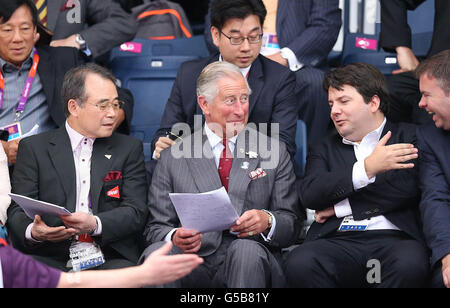 Der Prinz von Wales beobachtet die britische Susan Egelstaff beim Spielen der slowenischen Maja Tvrdy mit Dr. Kang Young Joong, dem Präsidenten der Badminton World Federation (links) und Gregory Verpoorten, dem Vizepräsidenten (rechts), am ersten Tag der Olympischen Spiele 2012 in London in der Wembley Arena in London. Stockfoto