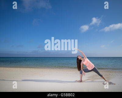 Junge Frau praktizieren Yoga am Strand von Motobu, Okinawa, Japan Stockfoto