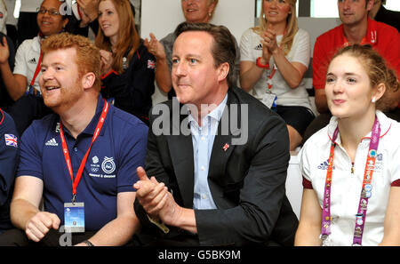 Premierminister David Cameron applaudiert der Goldmedaille, die die Ruderer der GB in Eton Dorney gewonnen haben, als er mit den Arbeitern im Team GB-Haus im Haupteinsatzerzentrum im Westfield Center in Stratford, im Osten Londons, saß. Stockfoto