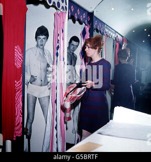 London ist „mit“. Eine Kundin in der John Stephens Boutique in der Carnaby Street geht in die Garderobe und findet dort Bilder von einem echten „Mann“. Stockfoto