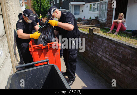 Die Bewohner beobachten, wie Polizisten in der Nähe von Tia Sharps Großmutter in New Addington, London, Mülltonnen durchsuchen. Stockfoto
