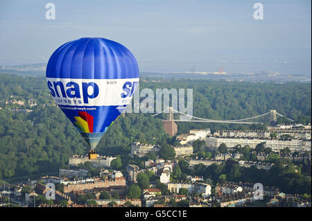 Ein Heißluftballon fliegt an der Clifton Suspension Bridge von Brunel in Bristol vorbei, in der die 34. Internationale Ballonfest von Bristol im Ashton Court Estate stattfinden wird, während sich Ballonfahrer aus der ganzen Welt zu dem größten Ballonevent in Europa versammeln. Stockfoto