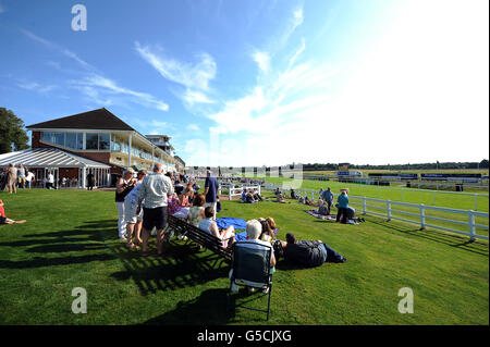 Pferderennen - Renn- und Musiknacht - Rennbahn Lingfield Park. Rennfahrer genießen die Sonne im Lingfield Park. Stockfoto