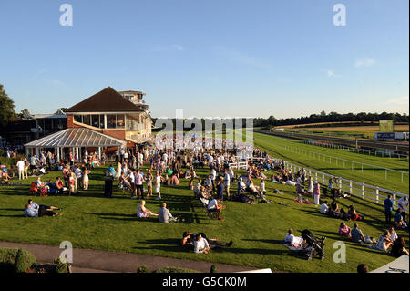 Pferderennen - Renn- und Musiknacht - Rennbahn Lingfield Park. Rennfahrer genießen die Sonne im Lingfield Park. Stockfoto