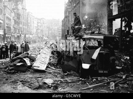 Rettungskräfte sorgen in High Holborn, London, inmitten der Schäden, die durch einen Bombenangriff der Luftwaffe während des Blitzes verursacht wurden, für einen stark beschädigten Bus. Stockfoto