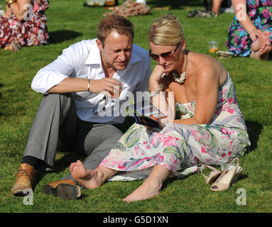 Pferderennen - Renn- und Musiknacht - Rennbahn Lingfield Park. Rennfahrer genießen die Sonne im Lingfield Park. Stockfoto