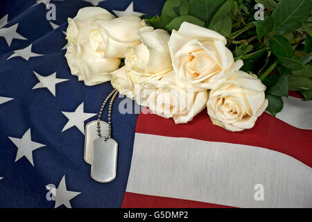 Weisse rose Bouquet und militärische Hundemarke auf amerikanische Flagge. Stockfoto