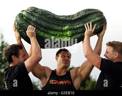 Der Gewichtheber Jonathan Walker (Mitte) aus Harrogate bereitet sich darauf vor, ein Mark mit einem Gewicht von 119 kg über seinen Kopf zu heben, nachdem es die „Giant Marrow“-Klasse bei der Harrogate Autumn Flower Show gewonnen hat. Das Knochenmark wurde von Peter Glazebrook aus Newark angebaut, der sechs erste Preise in den Giant Vegetable-Klassen auf der Messe erhielt. Stockfoto