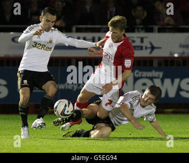 Crawleys Billy Clarke wird von Leon Britton (links) und Ben Davies (rechts) von Swansea City während des Spiels Capital One Cup, Third Round im Broadfield Stadium, Crawley, herausgefordert. Stockfoto