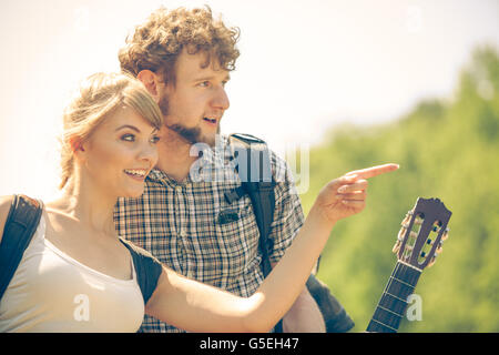 Abenteuer, Tourismus, Sommer Zeit zusammen genießen - junges Paar mit Gitarre Rucksack trampeln auf Wald Straße sonnige Landschaft wandern Stockfoto