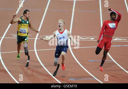 Der britische Jonnie Pfau (Mitte) feiert, als er die Linie überquert, um das 100-m-T44-Finale der Männer während der Paralympischen Spiele in London zu gewinnen. Stockfoto