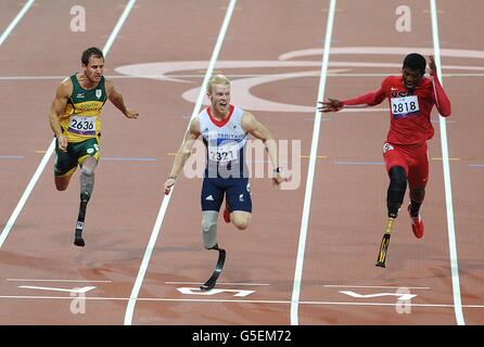 Der britische Jonnie Peacock (Mitte) überquert die Linie und gewinnt das 100-m-T44-Finale der Männer während der Paralympischen Spiele in London. Stockfoto