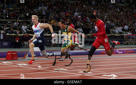 Der britische Jonnie Peacock (links) überquert die Linie und gewinnt das 100-m-T44-Finale der Männer während der Paralympischen Spiele in London. Stockfoto