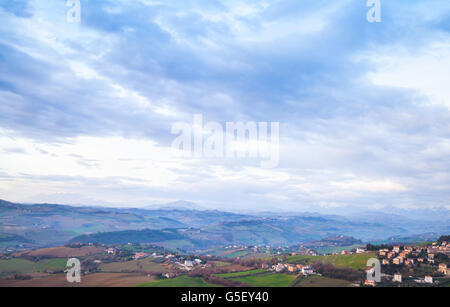 Ländliche Panorama der italienischen Landschaft. Provinz Fermo, Italien. Dorf auf einem Hügel unter dramatischen blauen Wolkenhimmel Stockfoto