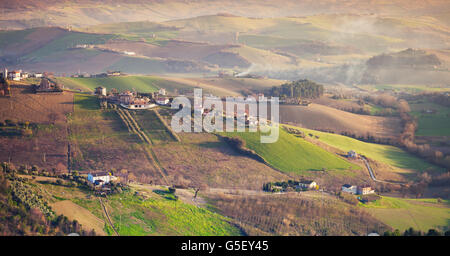 Frühling ländliche Panorama der italienischen Landschaft. Provinz Fermo, Italien. Bauernhöfe und grüne Felder auf Hügeln Stockfoto