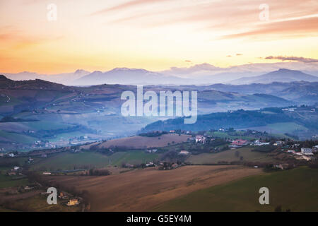 Morgen-Panorama der italienischen Landschaft. Provinz Fermo, Italien. Dörfer und Felder auf Hügeln unter bunten bewölktem Himmel Stockfoto