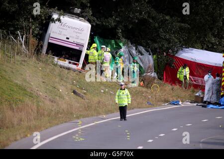 Rettungsdienste am Unfallort auf der A3 bei Hindhead in Surrey, wo drei Menschen starben und andere schwer verletzt wurden, als der Bus nach dem Zusammenprall mit einem Baum auf einem Damm umkippte. Stockfoto