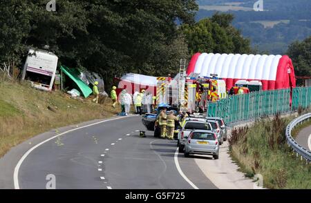 Rettungsdienste am Unfallort auf der A3 bei Hindhead in Surrey, wo drei Menschen starben und andere schwer verletzt wurden, als der Bus nach dem Zusammenprall mit einem Baum auf einem Damm umkippte. Stockfoto