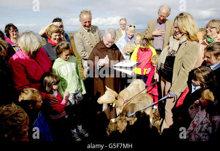 Pater Brian McKay von der Karmelitenkirche in der Whitefriar Street gießt während einer Segenszeremonie auf Howth Head in Dublin heiliges Wasser auf den Kopf einer von drei Ziegen. Als im Rahmen des Projekts „Goat's for Howth“ drei weibliche Ziegen auf den Berg freigesetzt wurden, um bei der Beweidung der Vegetation am Berghang zu helfen. Stockfoto