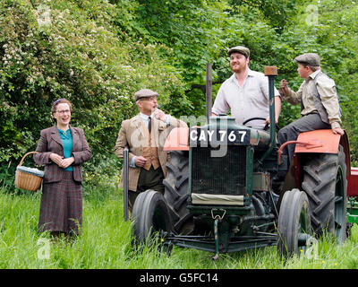 Die Squire und eine ältere Dame in vierziger Jahre Kleidung sprechen, ein Landwirt und Bauernhof junge auf Traktor Fordson Major. NB-WW2-Re-Eneactment. Stockfoto