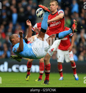 Vincent Kompany (links) von Manchester City versucht auf Druck von Arsenals per Mertesacker einen Freistoß Stockfoto